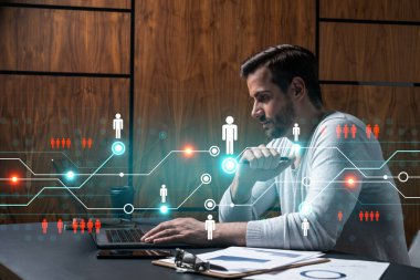 Yeni bir ağ geliştirmek için dizüstü bilgisayar kullanan ciddi bir Kafkasyalı yönetici. Çifte maruziyet. Sosyal medya hologramı.