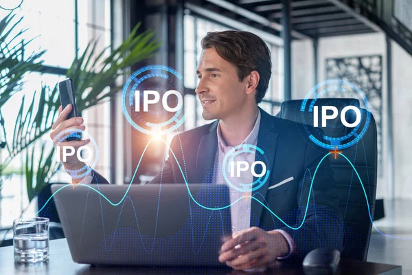 Бизнесмен в костюме использует смартфон для оптимизации стратегии IPO в корпоративных финансах. Картографическая голограмма на современном панорамном фоне офиса — стоковое фото