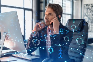 Takım elbiseli iş adamının, iş sürecinde yeni teknolojiler ima ederek gelişimi optimize etmek için konferans çağrısı var. Ofis arka planında panoramik pencereli yüksek teknoloji hologramı ve bağlantıları var