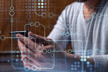 Programcı elinde akıllı bir telefon tutuyor ve tamamen yeni bir hizmet sunmak için yenilikçi bir uygulamayı test ediyor. Yakın çekim. Hologram teknik grafikleri. Dev takım kavramı.