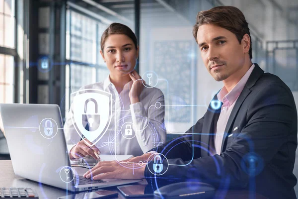 Forretningsmand og forretningskvinde arbejder sammen om at beskytte kunder fortrolige oplysninger og cybersikkerhed. IT hologram hængelås ikoner over kontor baggrund med panoramavinduer. - Stock-foto