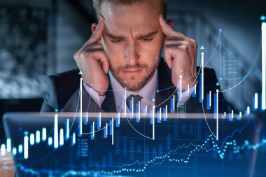 İş yerindeki takım elbiseli yakışıklı işadamı şirket finans fonundaki ticaret stratejisini optimize etmek için dizüstü bilgisayarla çalışıyor. Ofis arkaplanı üzerinde eski grafik hologramı