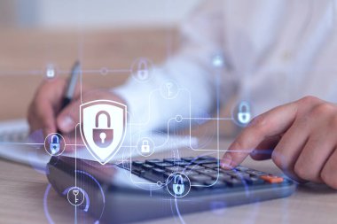 Bir iş adamı, hesap makinesi kullanarak siber güvenlik korumasında risk olasılığını hesaplıyor. Çalışma masasının üzerine asma kilit hologramı simgeleri. Resmi giysi.