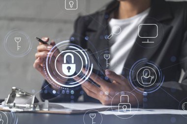 İş kadını siber güvenlikte risk olasılığını önlemek için sözleşmeyi resmi olarak imzalıyor. Telefonu kontrol ediyorum. Çalışma masasının üzerine asma kilit hologramı simgeleri.