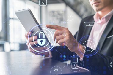 Takım elbiseli bir işadamı, müşterileri gizli bilgilerden korumak için siber güvenliği kontrol ediyor. IT hologramı modern panoramik ofis arkaplanı üzerine simgeleri kilitledi.