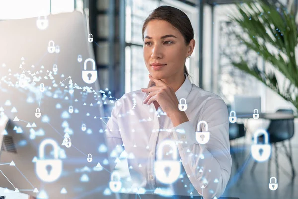 Atractiva mujer de negocios en camisa blanca en el lugar de trabajo trabajando con la computadora portátil para defender la seguridad cibernética del cliente. Concepto de protección de la información de clientes. Holograma de candado sobre fondo de oficina. — Foto de Stock