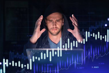 İş yerindeki kapüşonlu yakışıklı işadamı şirket finans fonundaki ticaret stratejisini optimize etmek için dizüstü bilgisayarla çalışıyor. Ofis arkaplanı üzerinde eski grafik hologramı