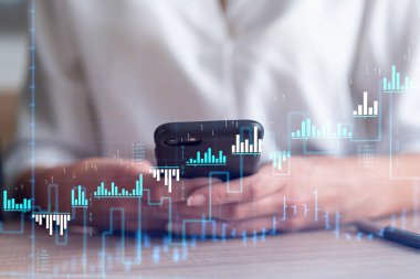 Elinde akıllı bir telefon tutan ve doğru yatırım çözümlerine ulaşmak için borsayı araştıran bir kadın tüccar. İnternet ticareti ve zenginlik yönetimi kavramı. Hologram Forex çizelgesi.