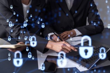 Uluslararası şirketin siber güvenliğini korumak için projede çalışan iki iş kadını. Belgelerle birlikte masadaki Hologram simgelerini kilitle.