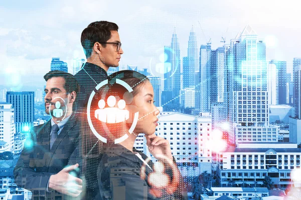 İş amaçlarına ulaşmak için sosyal medya pazarlama stratejisi üzerinde çalışan bir grup SMM uzmanı. Kuala Lumpur arkaplanı üzerinde hologram simgeleri.