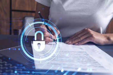 Sıradan giyinen bir iş kadını siber güvenlikte risk olasılığını önlemek için sözleşmeyi imzalıyor. Çalışma masasının üzerine asma kilit hologramı simgeleri.