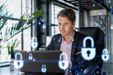 İş yerindeki yakışıklı iş adamı müşteri siber güvenliğini savunmak için dizüstü bilgisayarla çalışıyor. Müşterilerin bilgi koruması ve beyin fırtınası kavramı. Ofis arka planında asma kilit hologramı.