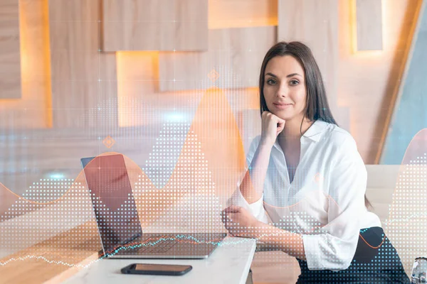 Attraktiv forretningskvinde i hvid skjorte på arbejdspladsen arbejder med laptop til at optimere handelsstrategi på corporate finance fond. Forex diagram hologram over kontor baggrund - Stock-foto