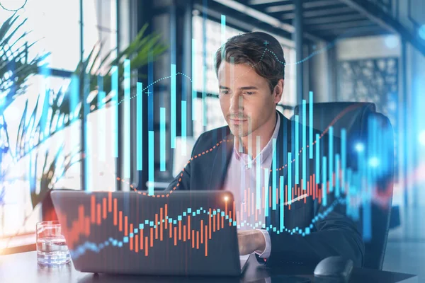 İş yerindeki takım elbiseli yakışıklı işadamı şirket finans fonundaki ticaret stratejisini optimize etmek için dizüstü bilgisayarla çalışıyor. Ofis arkaplanı üzerinde eski grafik hologramı — Stok fotoğraf