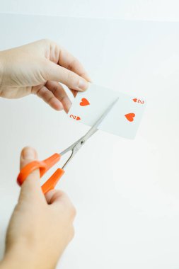 Kupa kartlarının ikisini makasla kesen eller.