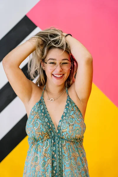 Fille blonde avec des lunettes posant avec un fond coloré — Photo