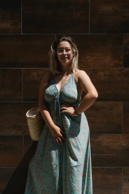 Gözlüklü sarışın kız koyu arkaplan pozu veriyor.