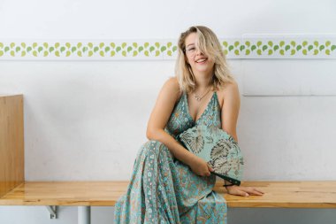 Genç sarışın kadın yelpaze kullanıyor.