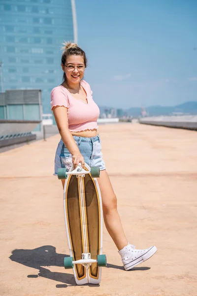 Portrait jeune femme blonde avec planche à roulettes portant des lunettes — Photo