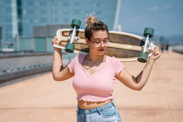 Porträtt ung blond kvinna med skateboard bär ett glas — Stockfoto