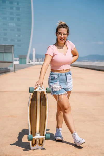 Portrait jeune femme blonde avec planche à roulettes portant des lunettes — Photo