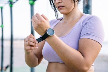 Latin bir kadın spor yapmadan önce saati koluna takar.