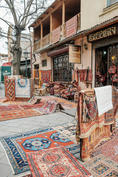 carpets laid out on the street near the store for sale