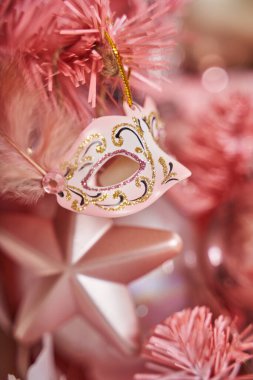 Tüylü ve yıldızlı pembe karnaval maskesi. Ağaçtaki güzel Noel oyuncakları.                               