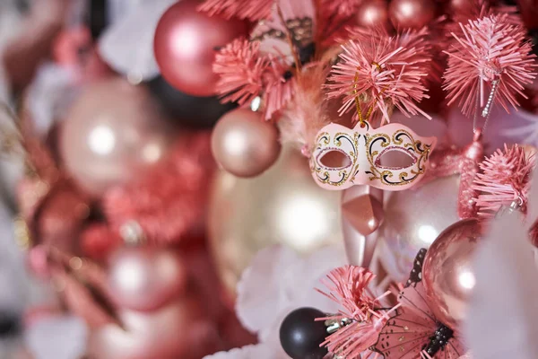 クリスマスツリーを飾る他のクリスマスボールの背景に美しい仮面舞踏会の形でピンクのクリスマスツリー上のクリスマスのおもちゃ — ストック写真