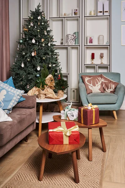 İskandinav tarzında bir oda. Köşede güzel bir Noel ağacı var. Masada hediyeli birkaç kutu var.                               