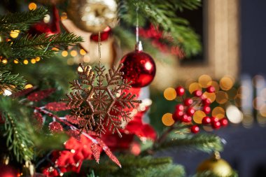 Kırmızı oyuncakların yanındaki ağaçta altın kar tanesi                                             