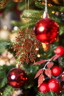 Ağaçtaki iki kırmızı topun arasında altın kar tanesi                                     