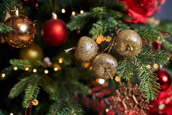 漂亮的金苹果是圣诞树上的装饰品 旁边是红色和金色的玩具 免版税图库照片