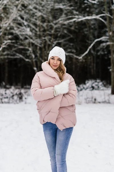 Genç ve güzel bir kadın kendini karlı bir parkta kalın bir cekete sarar.