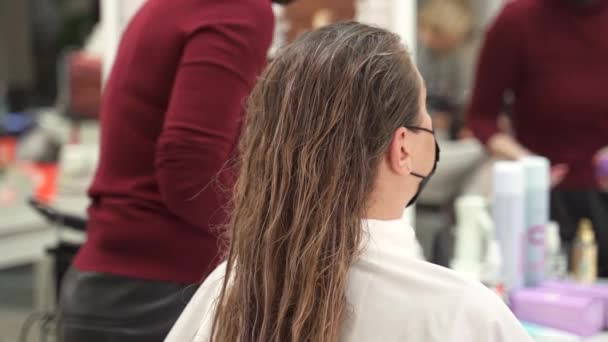 美容院里戴着防护面罩的理发师在湿发中使用一种特殊的定型产品 并通过发丝分发 — 图库视频影像