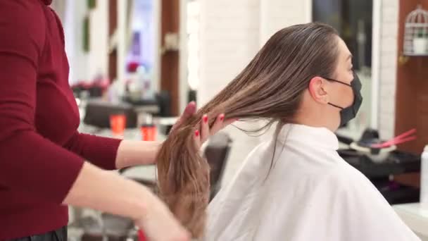 Парикмахер Расчесывает Длинные Влажные Волосы Девушки Защитной Маске Перед Зеркалом — стоковое видео
