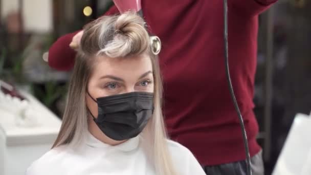 髪の毛をパンに巻き込んだマスクの女の子下の部分はヘアドライヤーで乾かします — ストック動画