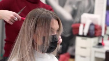 Siyah maskeli bir kız saçlarını tarar ve güzel bir tarakla eşit bir şekilde böler.