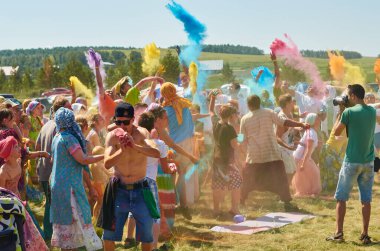 Aleksandrovsky, Rusya 2015.06.21 Hare Krishna 'lı bir kalabalık Holi festivalinde eğleniyor ve havaya renkli resimler atıyor.