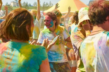 Aleksandrovsky, Rusya 2015.06.21 Hare Krishna 'lı bir kalabalık renk festivalinde eğleniyor ve dans ediyor.