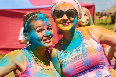 aleksandrovsky, russia 2015.06.21 two cheerful european girls in colored paint on clothes and face at the festival of colors holi