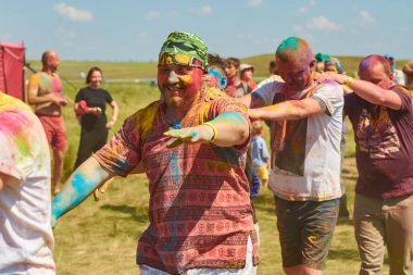 Aleksandrovsky, Rusya 2015.06.21 Hare Krishna 'lı bir kalabalık renk festivalinde eğleniyor ve dans ediyor.