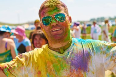 Rusya, Arkaim 2015.06.21 Renk Festivali 'nde vücudu ve yüzü renkli boyalarla kaplı neşeli genç Avrupalı adam.