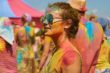 aleksandrovsky, russia 2015.06.21 beautiful graceful girl in round glasses covered with colored paint at the holi holiday