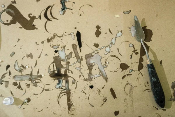 Bir spatula boya kalıntılarıyla boyanmış el sanatları kağıdının üzerinde yatar.