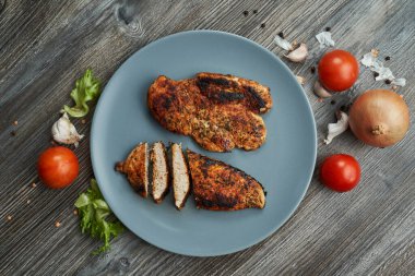 Tabakta iki kızarmış tavuk göğsü. Taze sebzeler yakında.