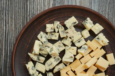 İki çeşit peynirin küp şeklinde kesildiği kahverengi tabak. Biri mavi küflü, diğeri ikinci Mazdam. Yukarıdan bak. Tabak tamamen görünür değil.