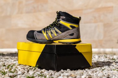 Tehlikeli işler için yüksek parmaklı güçlendirilmiş güvenlik botlarının ön çekimi; gri, siyah ve sarı bağcıklı.