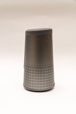 Uzatılmış gri hoparlör şeklindeki silindir, bluetooth ile beyaz bir arkaplanda izole edilmiş.