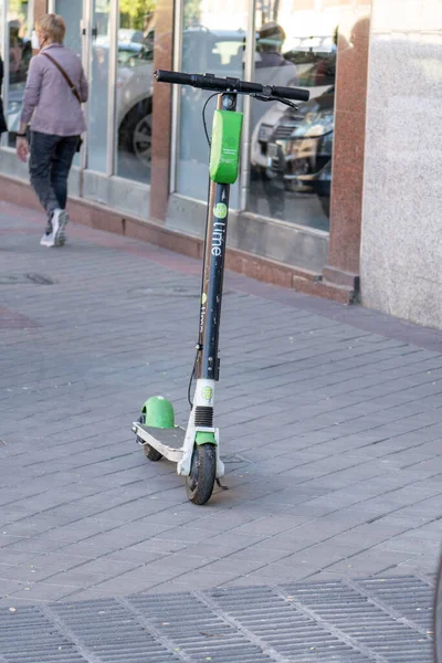 Madrid İspanya. 6 Nisan 2021. Kaldırım kenarına park etmiş Lime şirketinin uygulaması ile birlikte kiralık bir elektrikli scooter 'ın dikey çekimi..